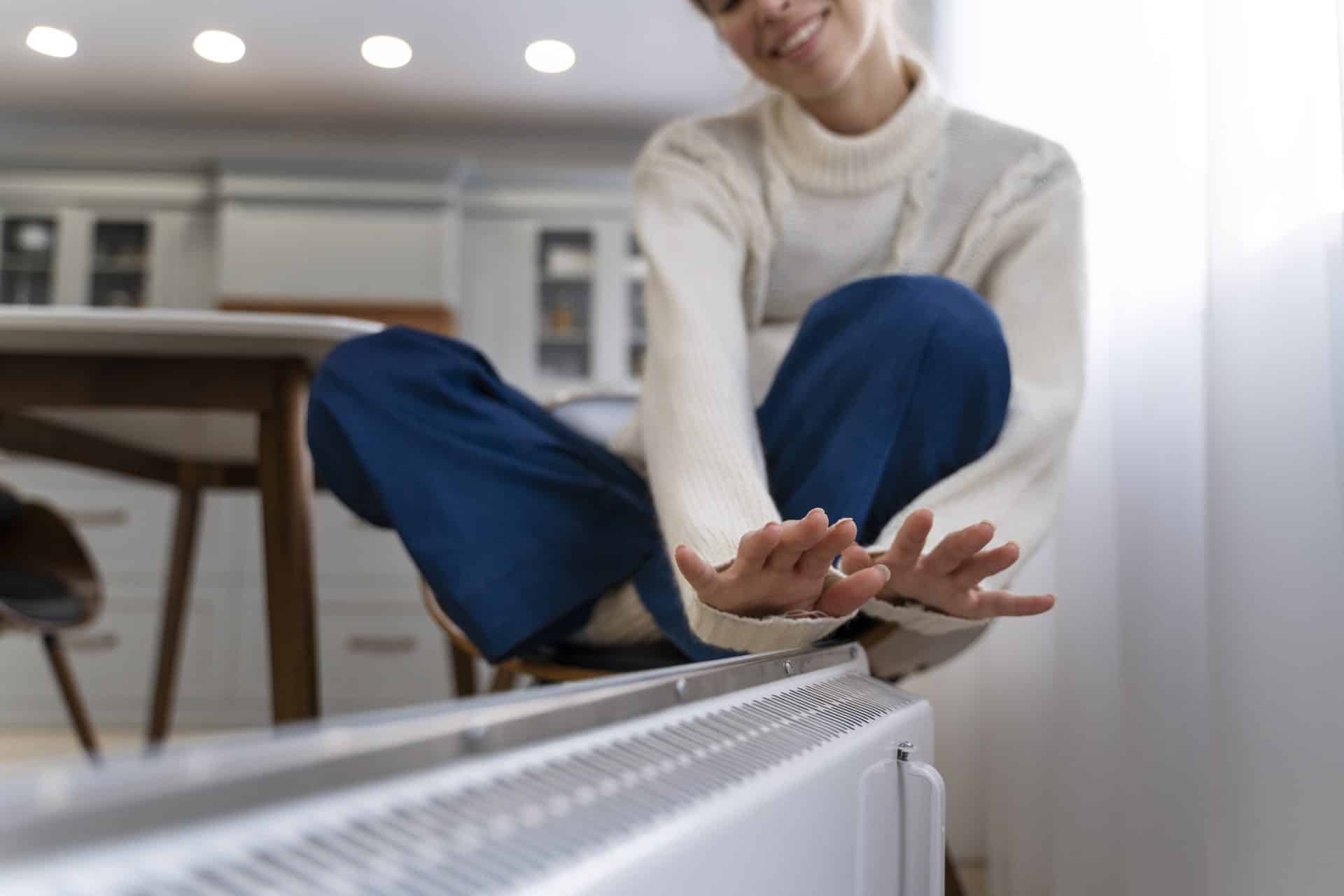 smiley woman sitting near heaters at home